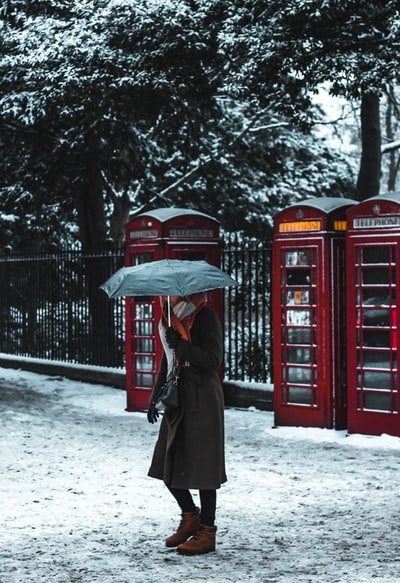 电话亭附近一名妇女打着雨伞